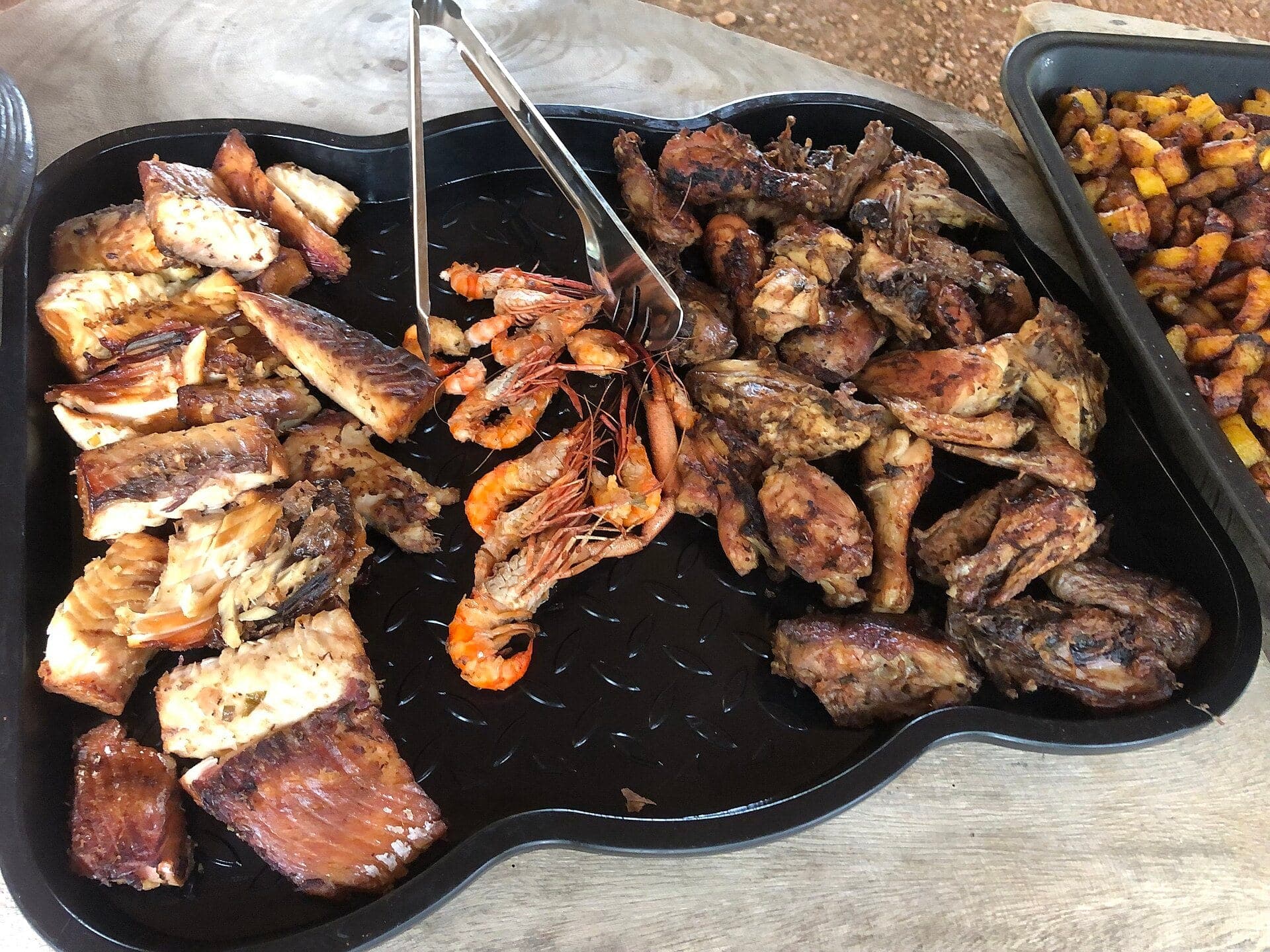 Un plateau de poisson et de poulet braisés, avec des crevettes et des plantains