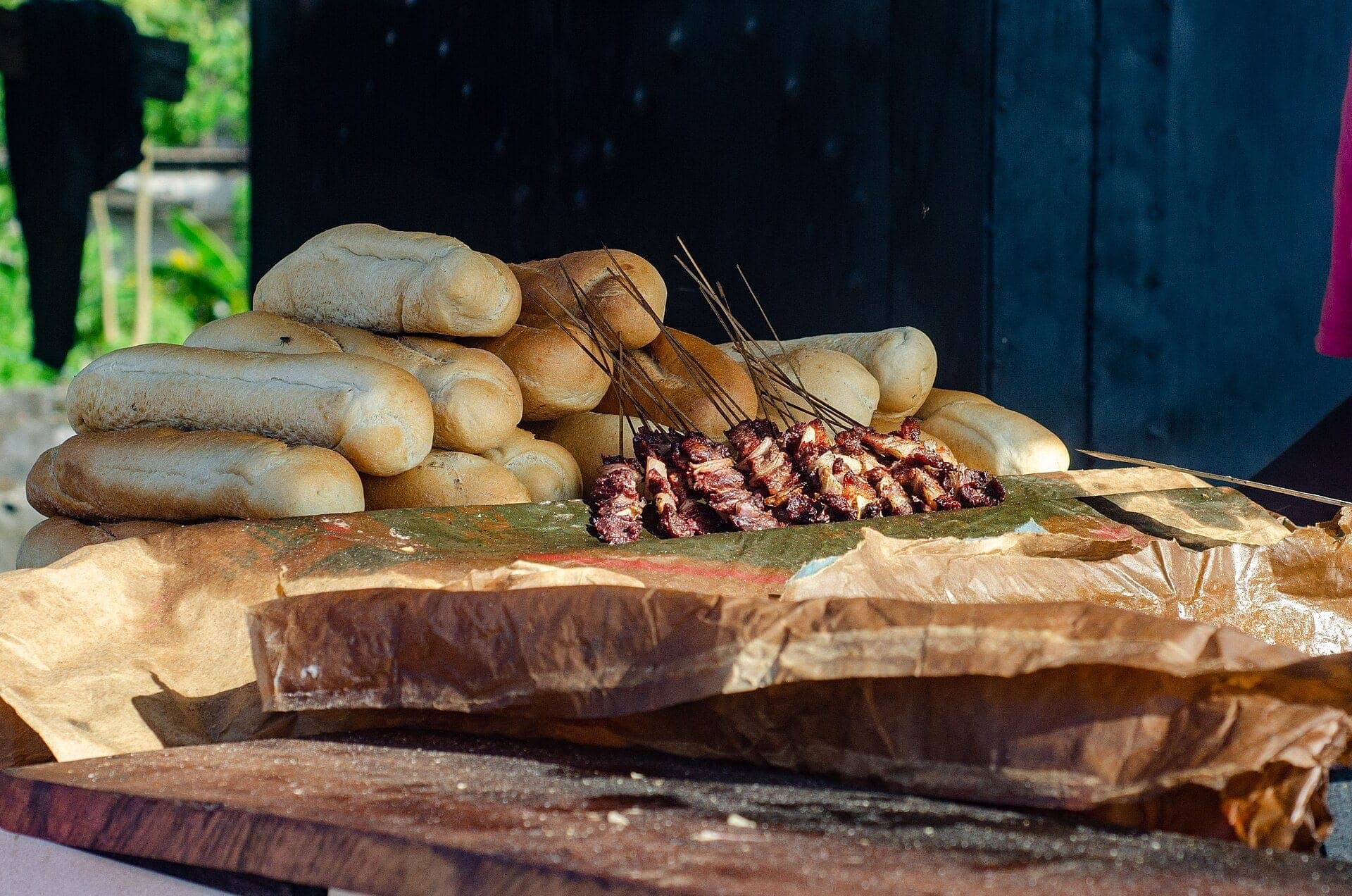 Soya skewers and loaves of bread lined up on a stall in Kribi