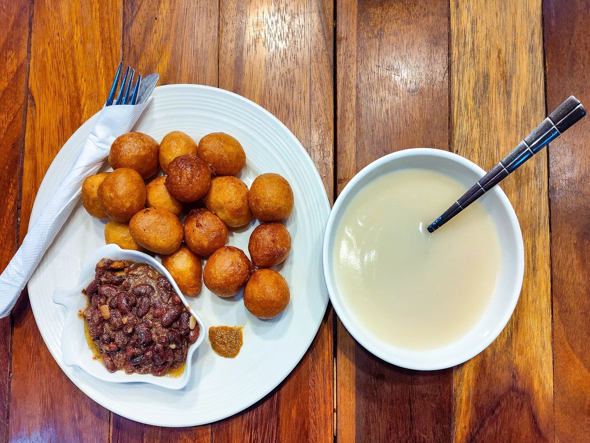 Une assiette de beignets et de haricots, avec un bol de bouillie