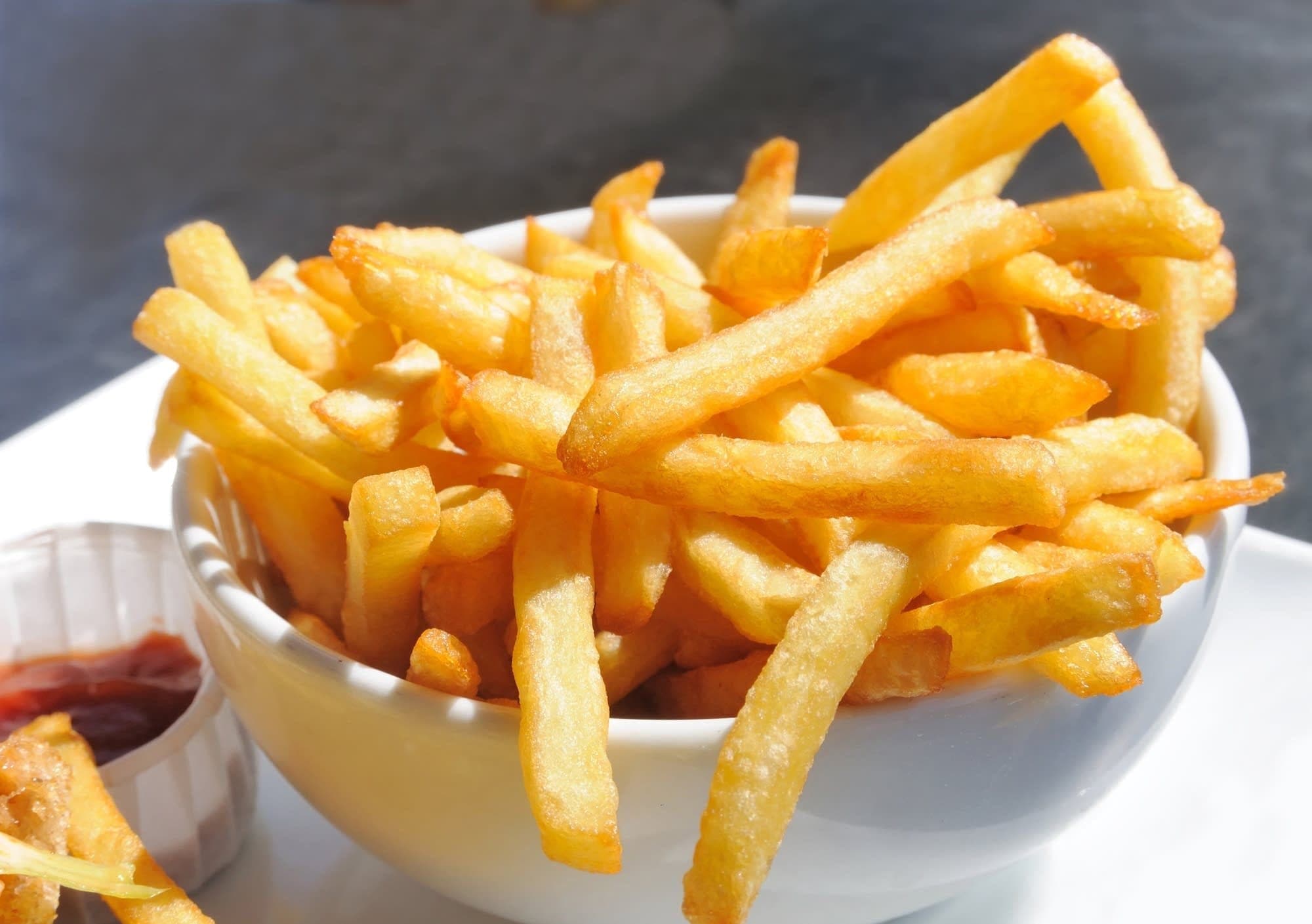 Un bol de frites dorées avec une petite sauce tomate