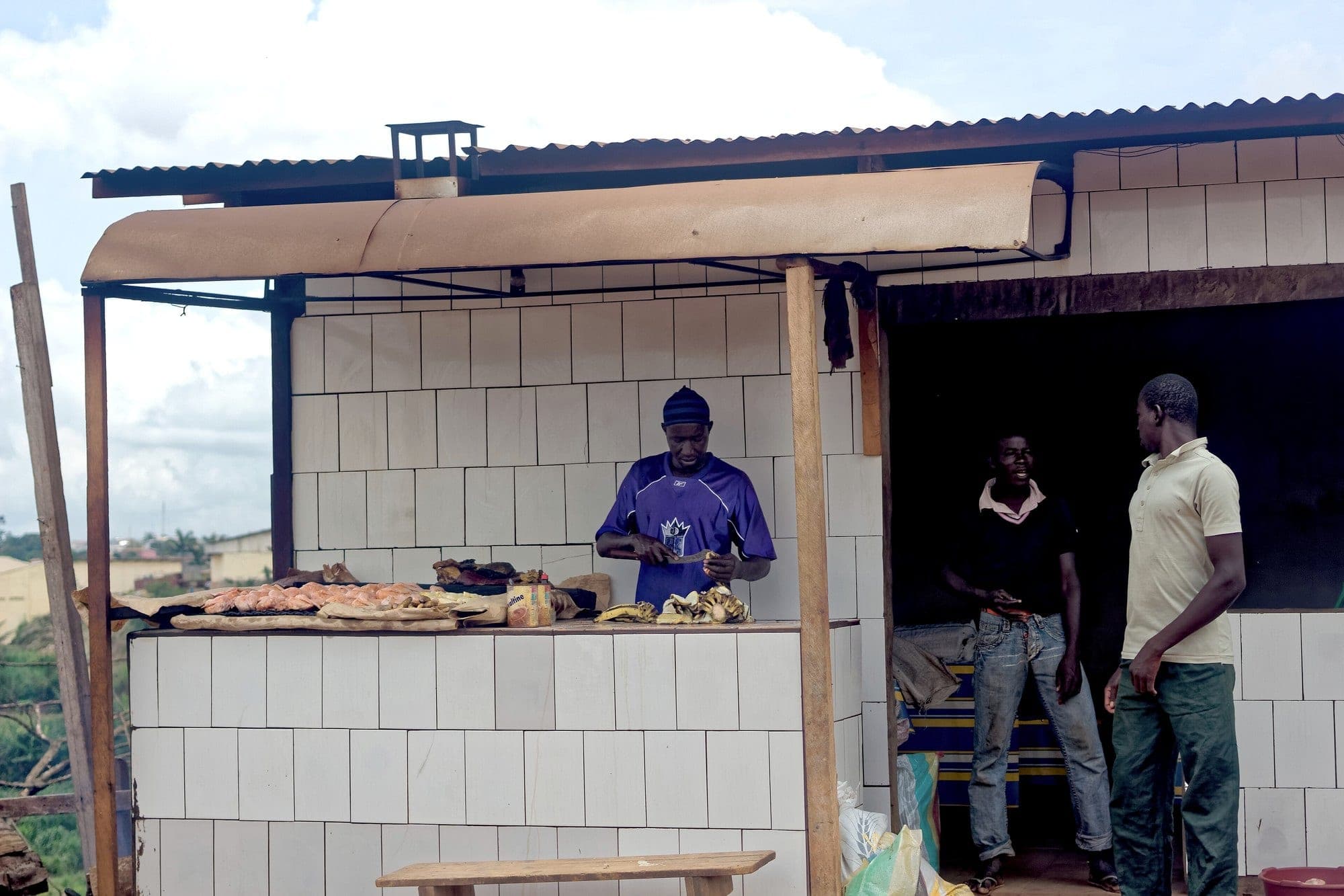 Une petite cuisine en plein air à Yaoundé, avec un cuisinier derrière son comptoir