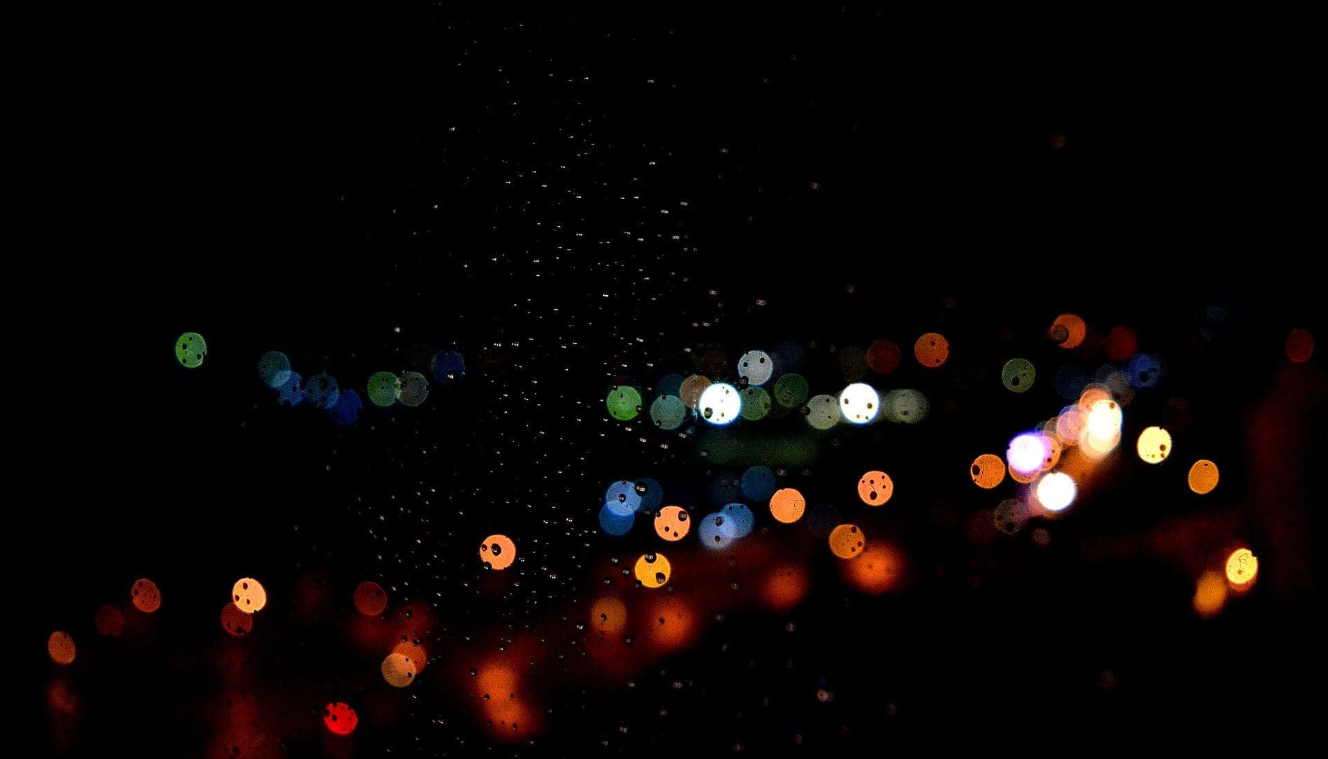Les lumières de Yaoundé la nuit, floues derrière des gouttes de pluie