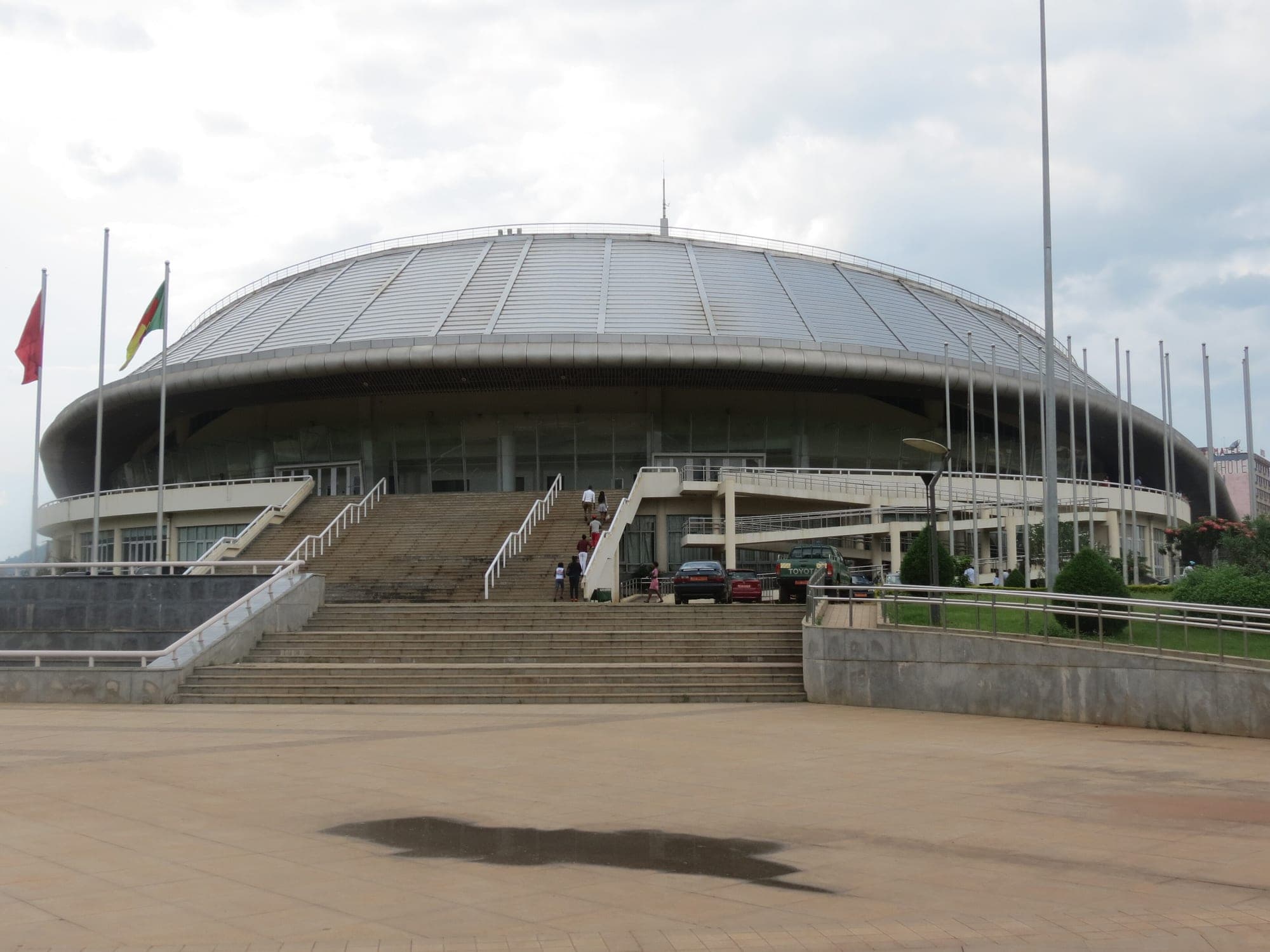 Le Palais polyvalent des sports de Yaoundé, grand bâtiment rond au toit argenté, vu depuis son esplanade