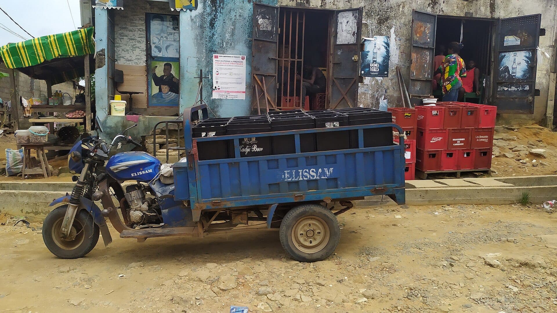 Un tricycle chargé de casiers de bière devant un dépôt, à Douala